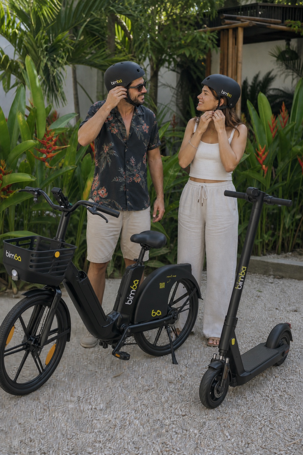 Man and woman putting on Bimba helmets beside a Bimba electric bike and OKAI ES400A scooter in Santa Teresa