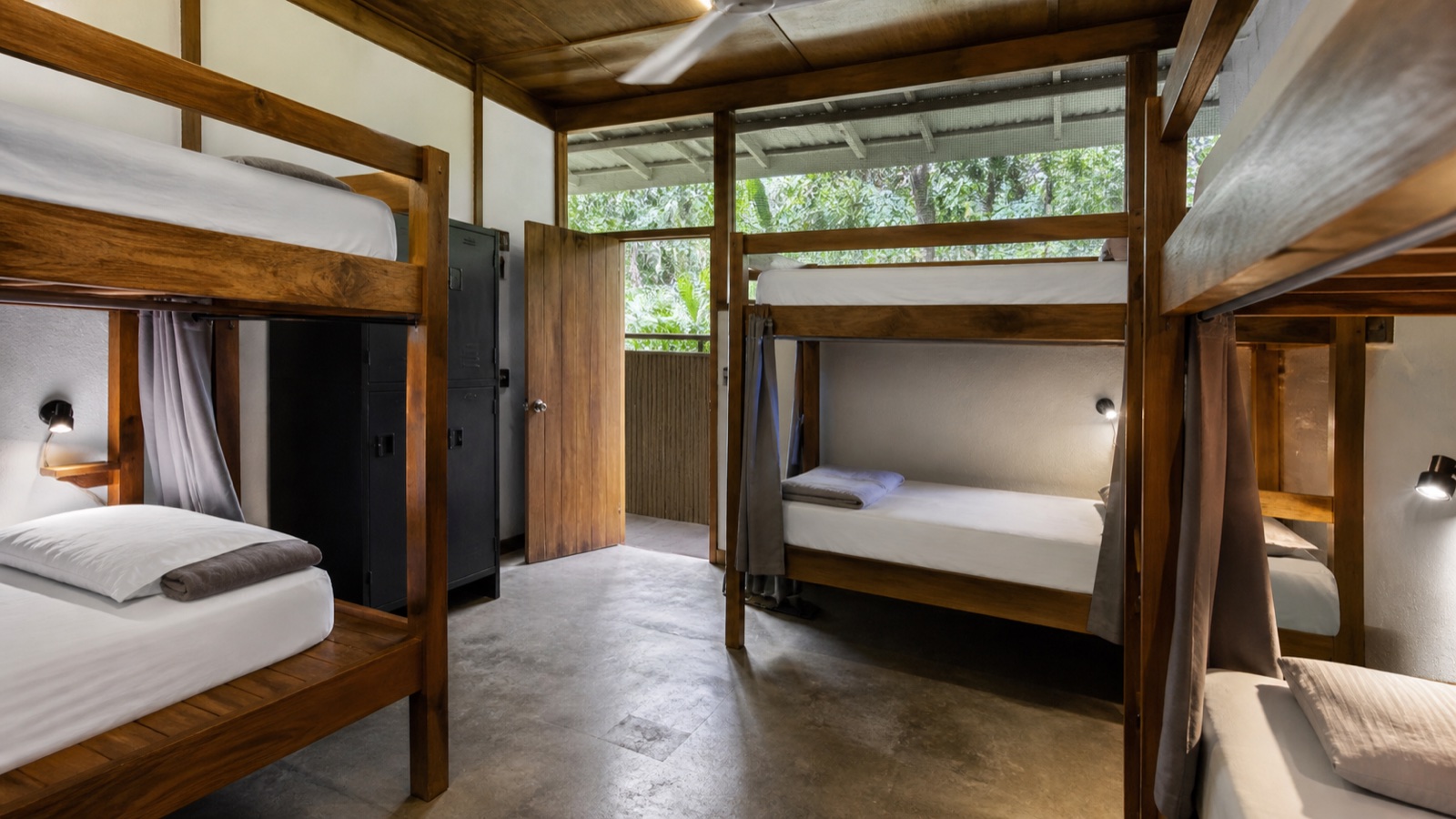 Clean six-bed tropical hostel dorm with curtains, reading lights, fan and secure lockers