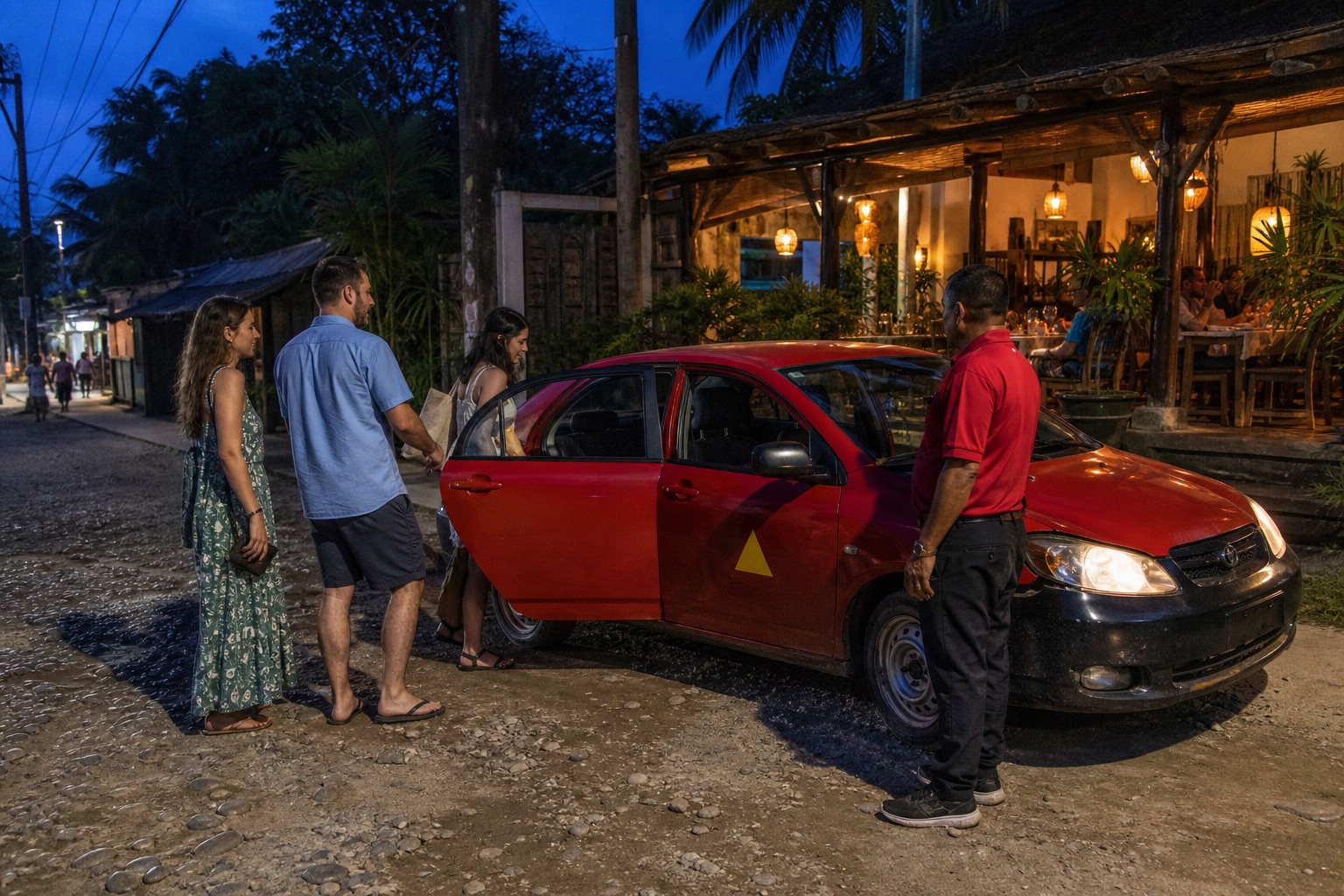 Travelers boarding a red Costa Rican taxi after dinner in Santa Teresa