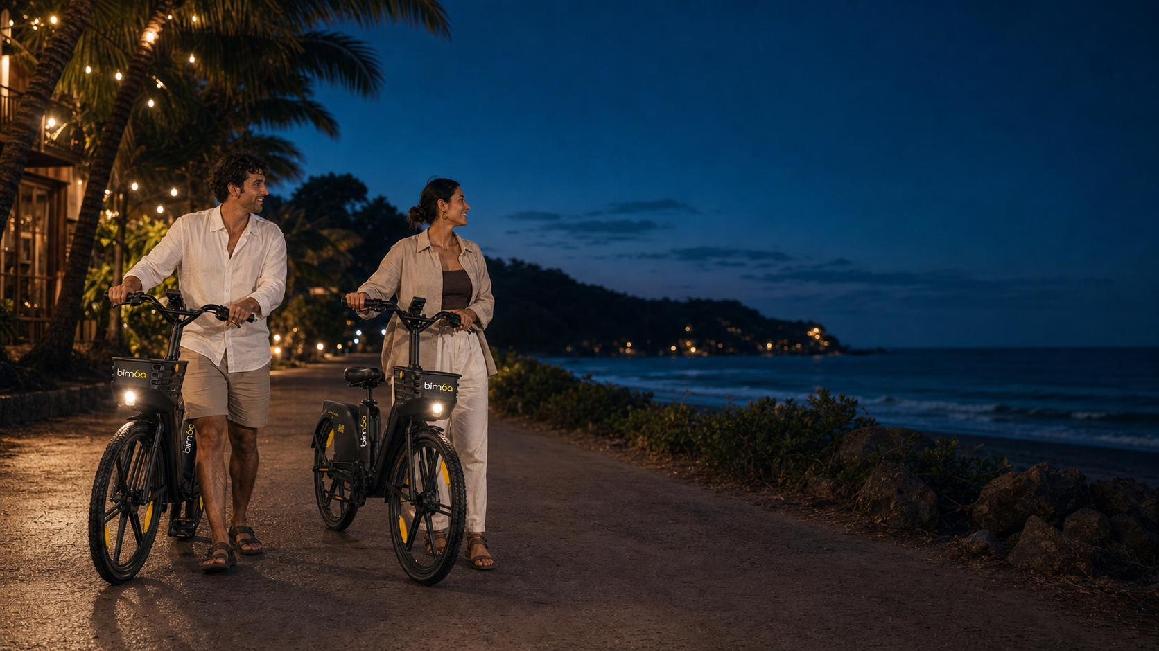 Two people walking Bimba electric bikes beside the coast in Santa Teresa at blue hour