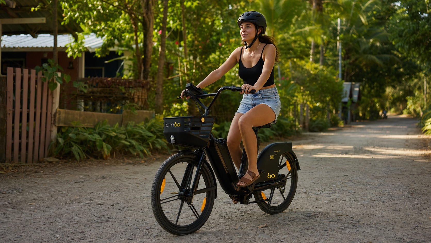 Helmeted rider using a black Bimba electric bike on an unpaved tropical road in Santa Teresa