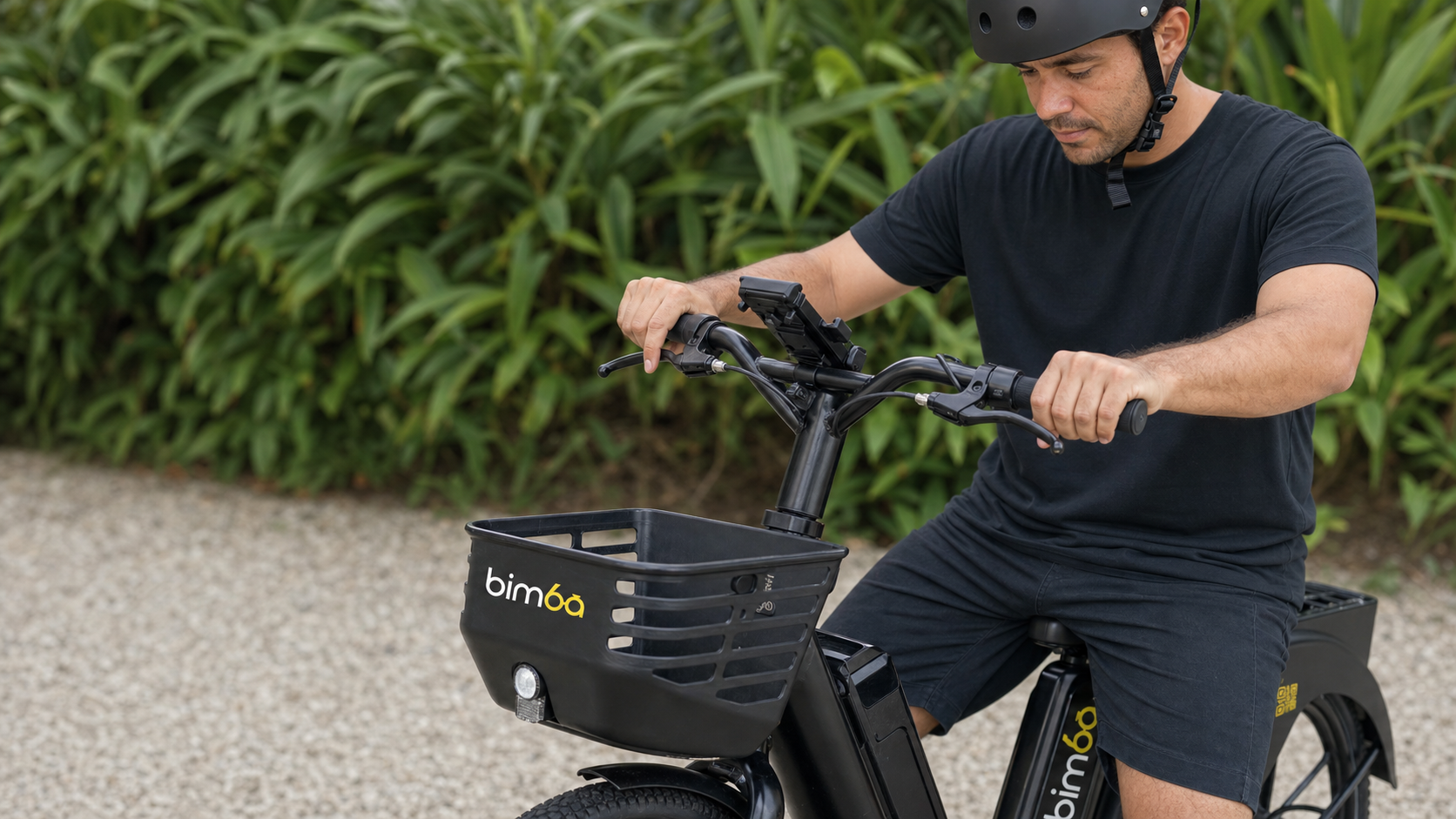 Helmeted rider checking both brake levers on a stationary black Bimba e-bike